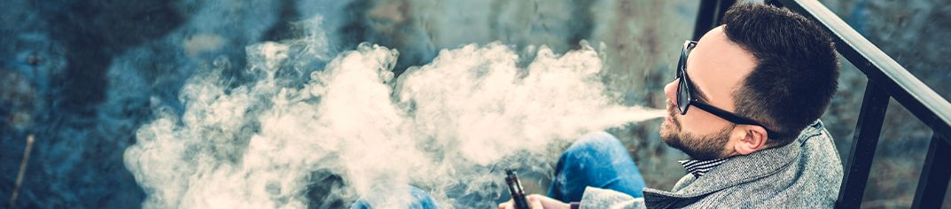 Barbat vapand dintr-o tigara electronica
